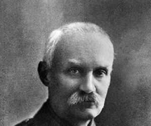 A middle-aged man with a receding hairline and a thick mustache, wearing a military uniform with medals on his chest.