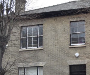 A two-story brick building with a dark front door, sash windows, and a CIS Cambridge International School sign by the entrance.