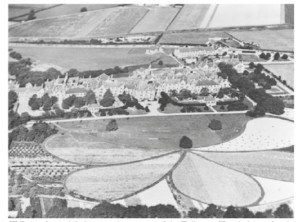 Aerial view of the large Fulbourn Hospital building complex surrounded by farmland and formal, petal-shaped garden plots.