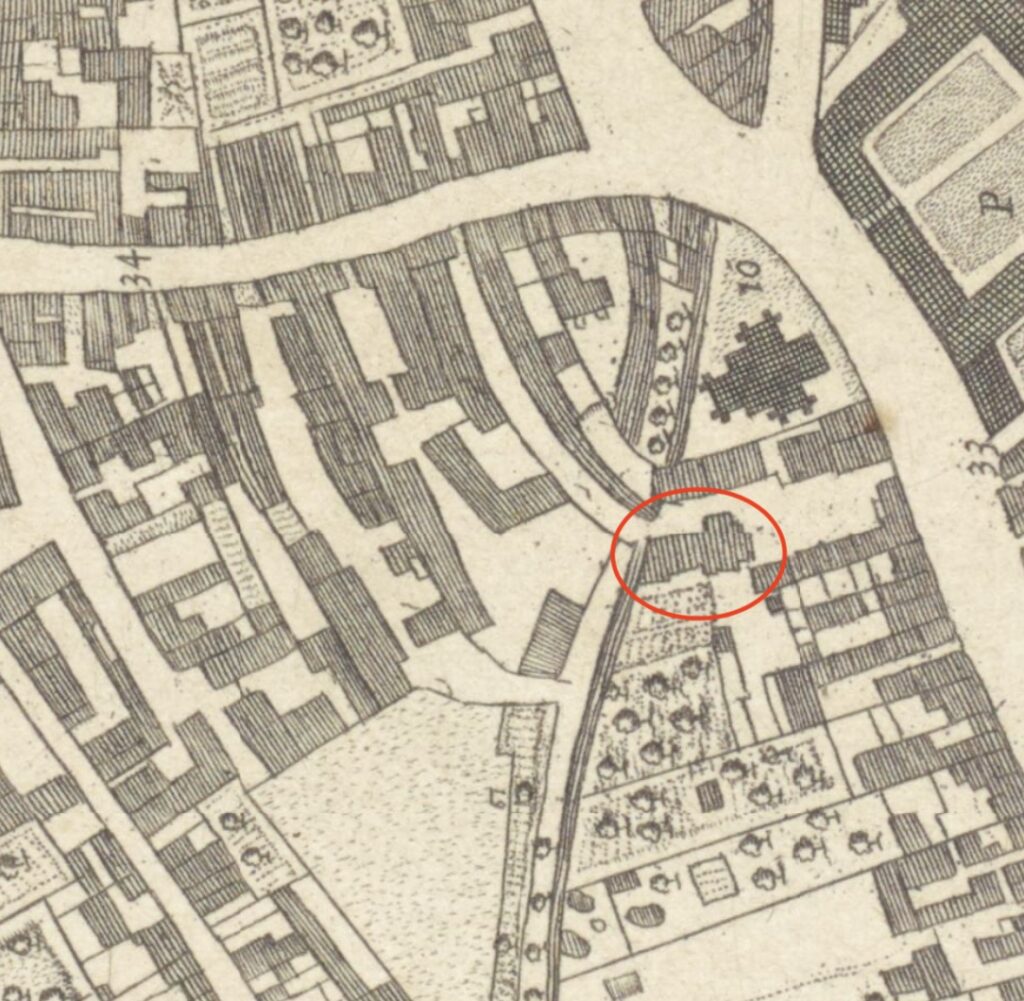 A detail from a historical map showing a cluster of buildings, with a red circle highlighting one specific building footprint.